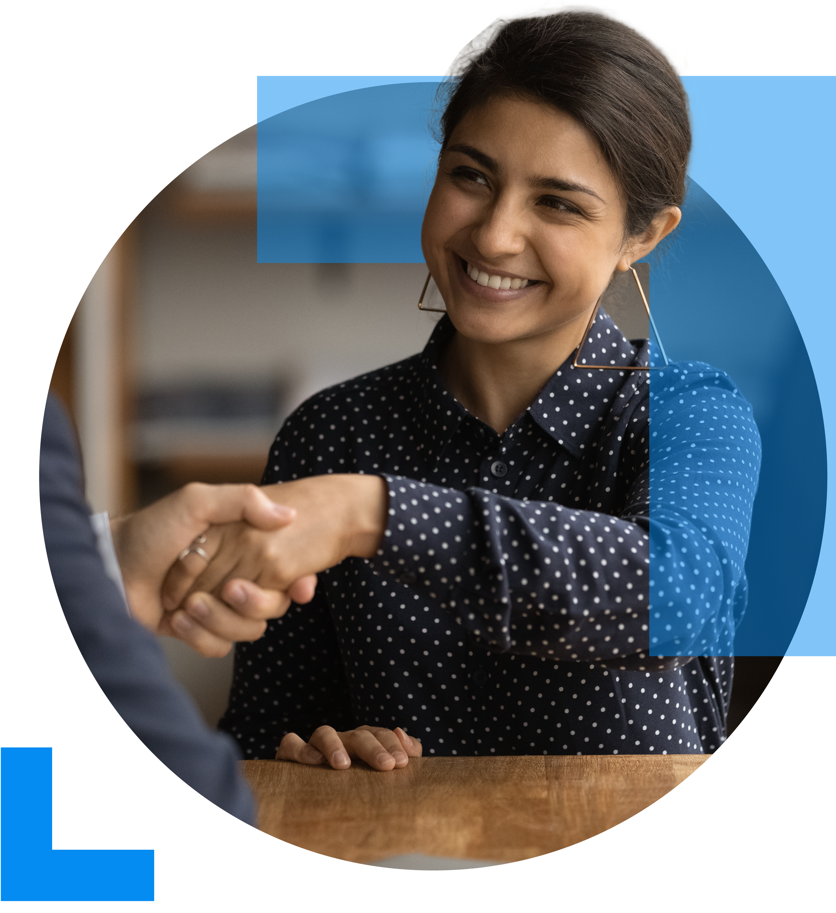 A woman shakes hands with another individual accross a table in an interview setting, representing the Recruitment sector.