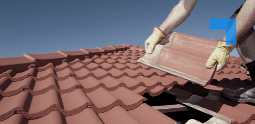 A workman fits a replacement roof tile onto a roof.