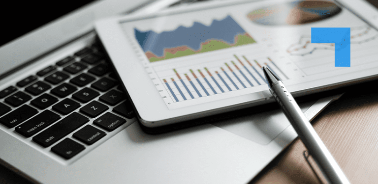 A laptop keyboard with a tablet placed on top displaying colorful business charts and graphs, with a pen resting on the tablet, representing financial analysis or data reporting.