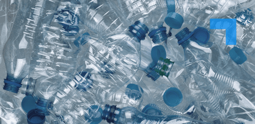 A pile of crushed, clear plastic water bottles with blue caps, recycling waste background highlighting plastic pollution and sustainability.