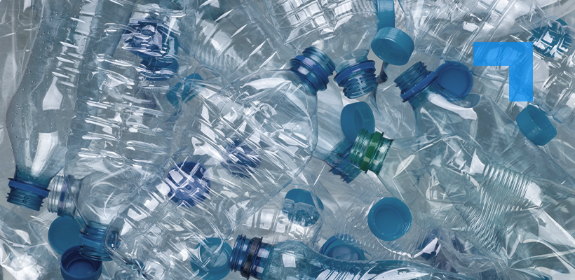 A pile of crushed, clear plastic water bottles with blue caps, recycling waste background highlighting plastic pollution and sustainability.